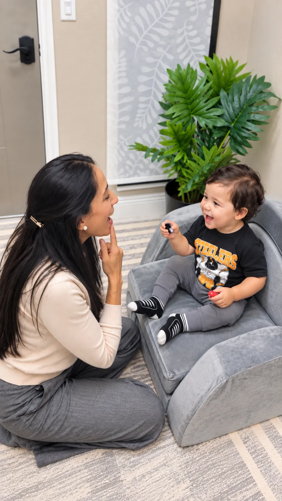 Karin modeling a speech sound for a smiling toddler during a play-based session